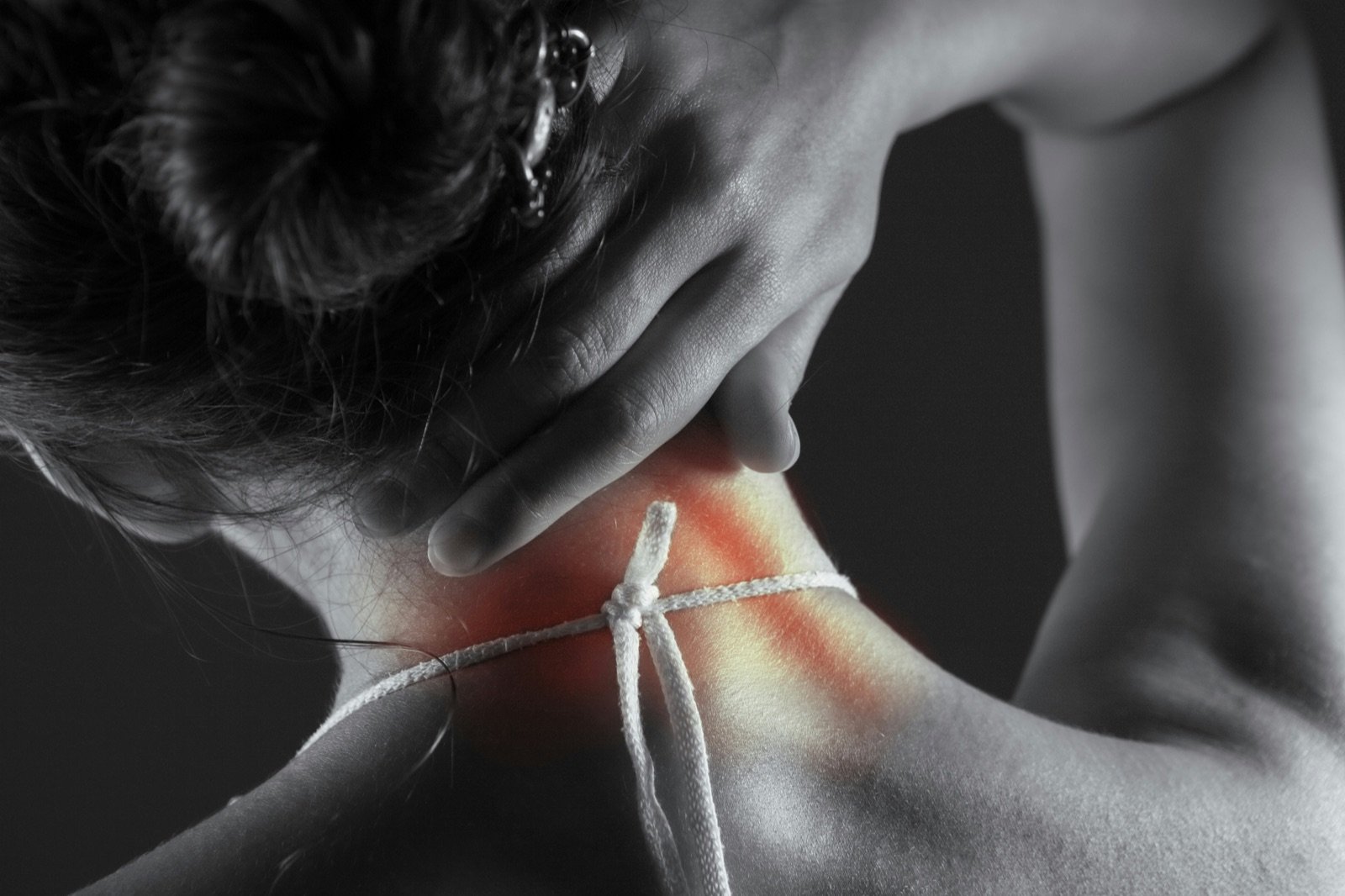 Black-and-white photo of a woman holding the back of her neck, with the painful area highlighted in red