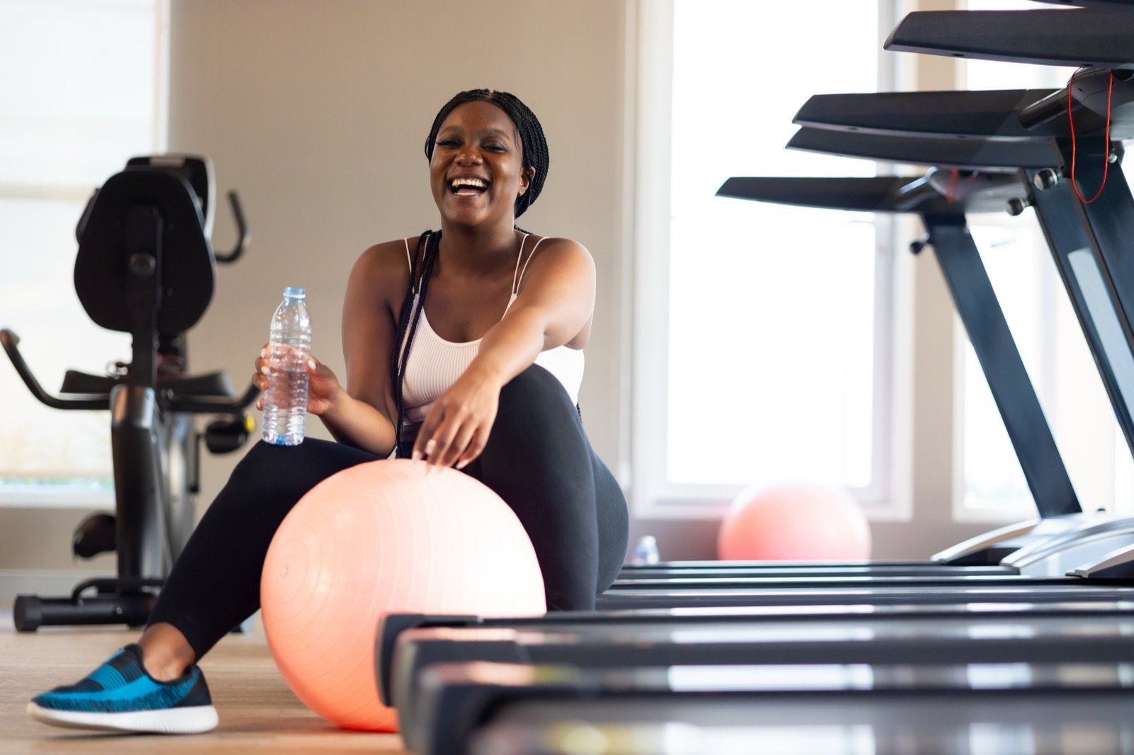 Woman laughing on an exercise ball in a gym after a strength-focused workout